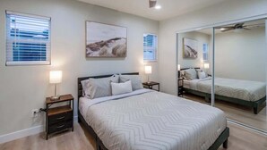 Une chambre à coucher avec un lit, des tables de chevet, un ventilateur de plafond et un grand miroir.