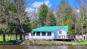 A lakeside house with a green roof, a dock, and a deck. - Lake Rosseau Water's Edge Retreat (Port Carling)