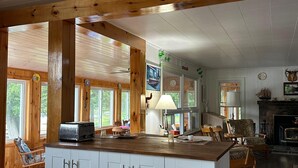 A spacious kitchen with a central island, wooden beams, and large windows. - Lake Rosseau Water's Edge Retreat (Port Carling)