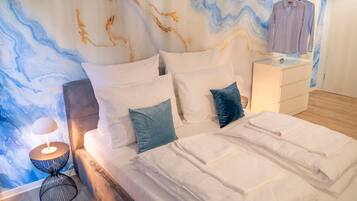 Ein ordentlich gemachtes Bett mit weißen Leinen, ein Nachttisch mit einer Lampe und eine Wand mit marmorartigem Dekor.