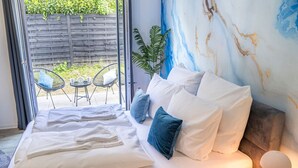 Un lit avec du linge de lit blanc, une plante bleue et un mur en marbre.