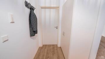 A hallway with a coat rack, a door, and a light switch.
