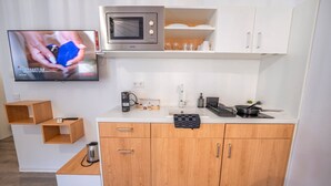 Une petite cuisine équipée d’un four à micro-ondes, d’une machine à café et d’un petit évier.