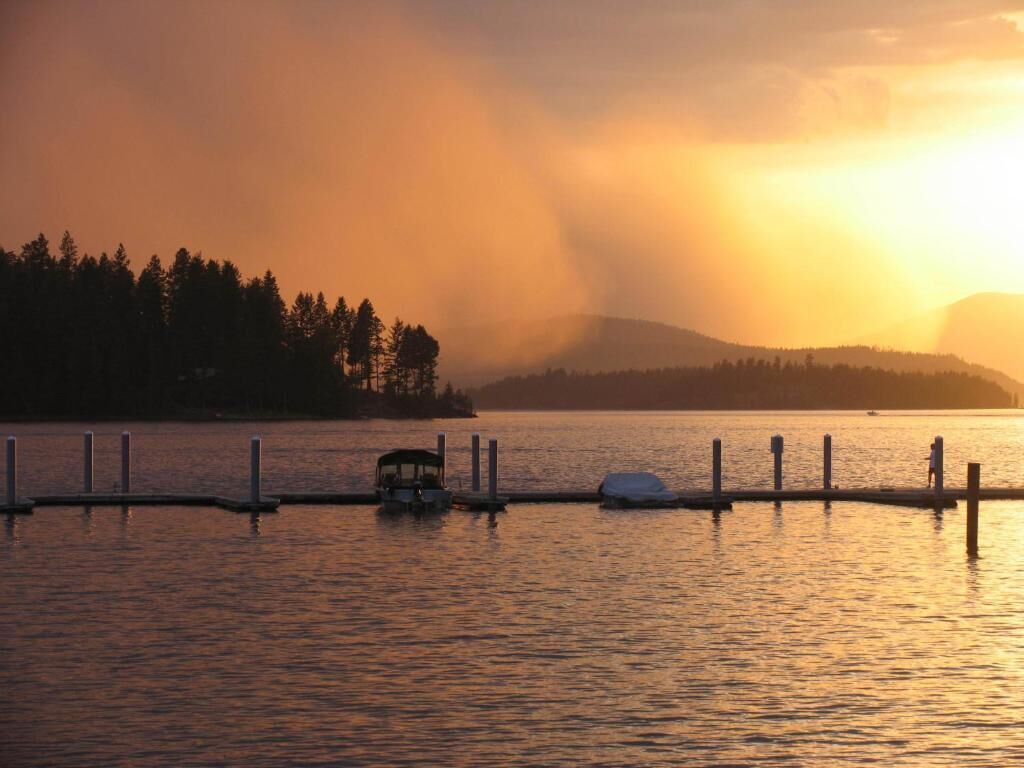 Un lago tranquilo al atardecer con un muelle y un pequeño bote.