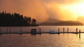 Un lago tranquilo al atardecer con un muelle y un pequeño bote.