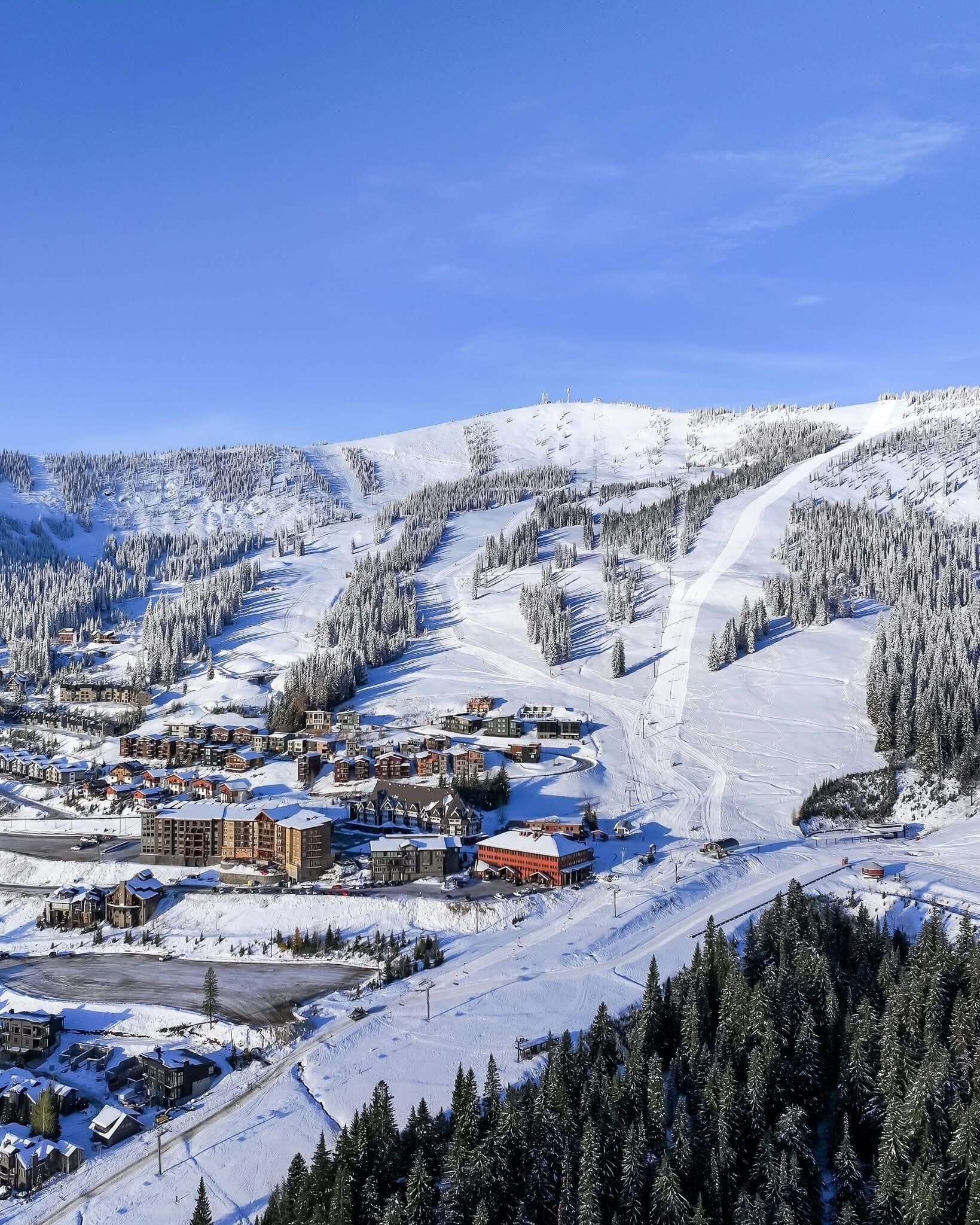 Un centro de esquí cubierto de nieve con varios edificios, incluyendo alojamientos y una zona de remontes.