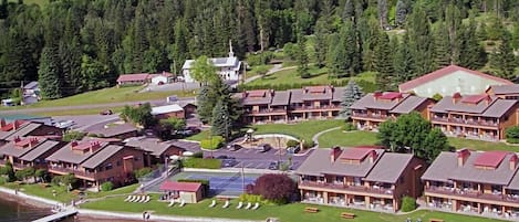 Un complexe hôtelier comprenant plusieurs bâtiments, une piscine et une jetée qui s’avance dans un lac.