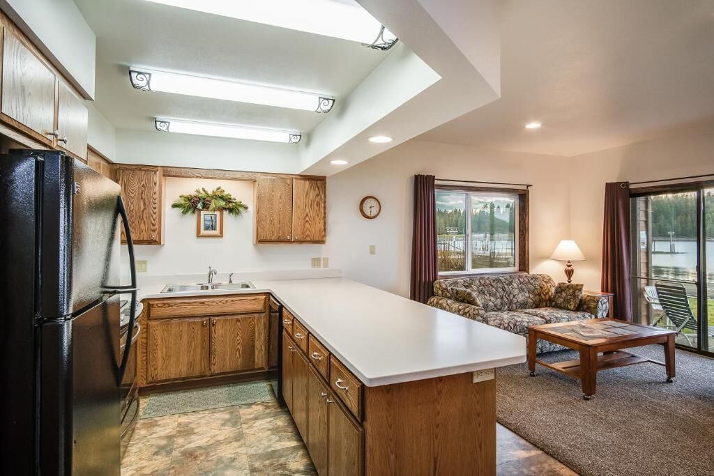 A kitchen with wooden cabinets, a refrigerator, a large island, and a dining area with a sofa and table.