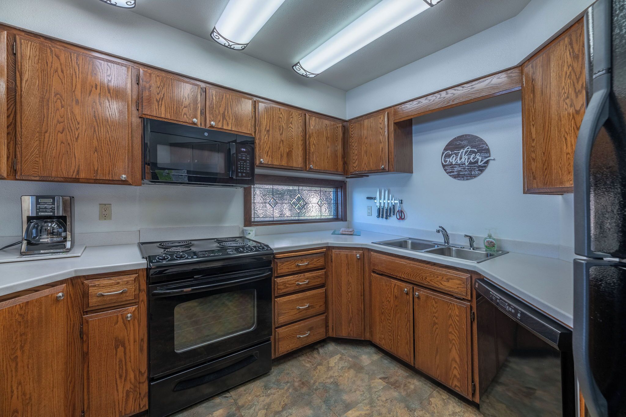 A kitchen with wooden cabinets, a microwave, a stove, a dishwasher, and a window with a view.