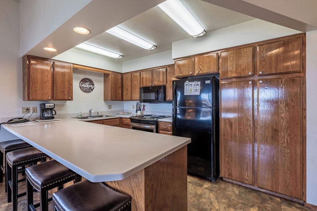 A kitchen with wooden cabinets, a stainless steel refrigerator, a microwave, and a coffee maker.