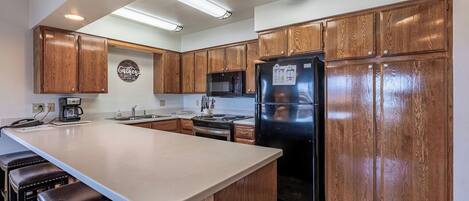 A kitchen with wooden cabinets, a stainless steel refrigerator, a microwave, and a coffee maker.