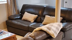 A brown leather sofa with a plaid throw blanket, a wooden coffee table, and a marble floor. - Cozy, beautiful apartment with lots of amenities! 3 miles from downtown fun! (Columbus)
