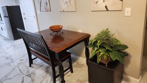 A dining area with a wooden table, a bowl, a chair, and a potted plant. - Cozy, beautiful apartment with lots of amenities! 3 miles from downtown fun! (Columbus)