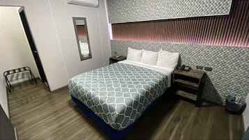 A hotel room with a bed, bedside tables, a mirror, and a wall with a textured pattern.