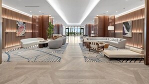 Un hall d’hôtel moderne doté d’un espace salon central, de lambris en bois et offrant une vue sur l’extérieur.
