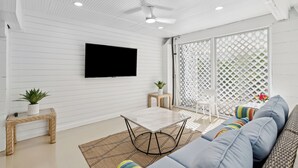 A modern living room with a flat-screen TV, a sofa, a coffee table, and a ceiling fan. - 42 Bradley Beach @ Folly Field Beach | Pool | Steps to Sandy Shores | Next to Driessen Beach Park (Hilton Head Island)