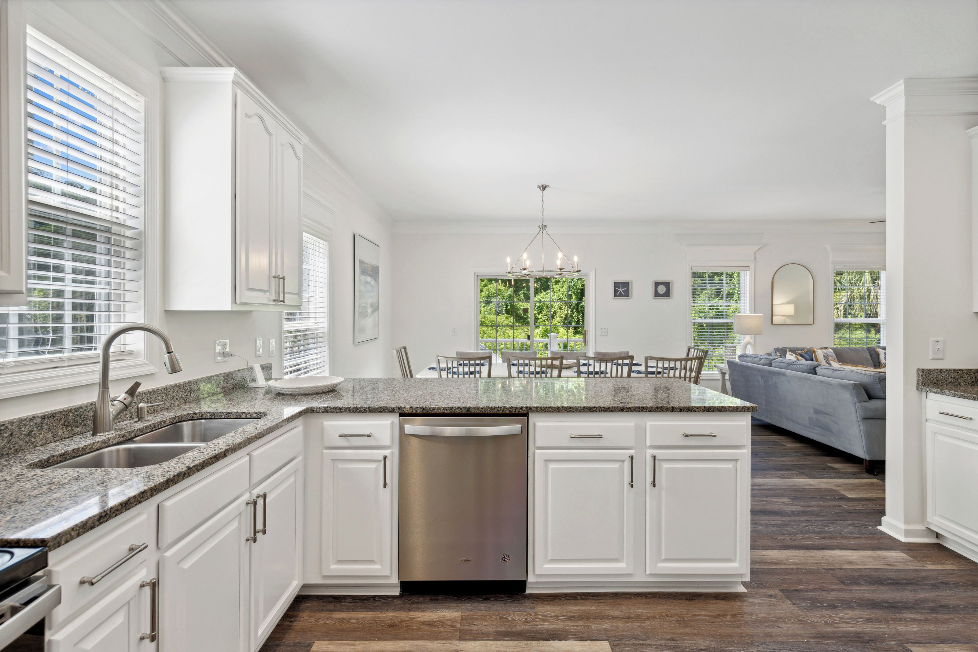 A modern kitchen with white cabinetry, a granite countertop, and a built-in dishwasher.