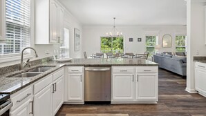 A modern kitchen with white cabinetry, a granite countertop, and a built-in dishwasher. - 42 Bradley Beach @ Folly Field Beach | Pool | Steps to Sandy Shores | Next to Driessen Beach Park (Hilton Head Island)