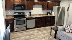 Una cocina moderna con armarios de madera, electrodomésticos de acero inoxidable, encimera de granito y horno integrado.