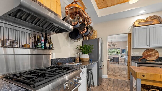 A modern kitchen with stainless steel appliances, a gas stove, and a variety of cookware hanging above the stove. - Monthly Rental - Crimson 4 BR Cabin By Tahoe Getaways - Walk Downtown Truckee (Truckee)