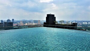 Une piscine à débordement située sur le toit, avec la silhouette de la ville en arrière-plan.