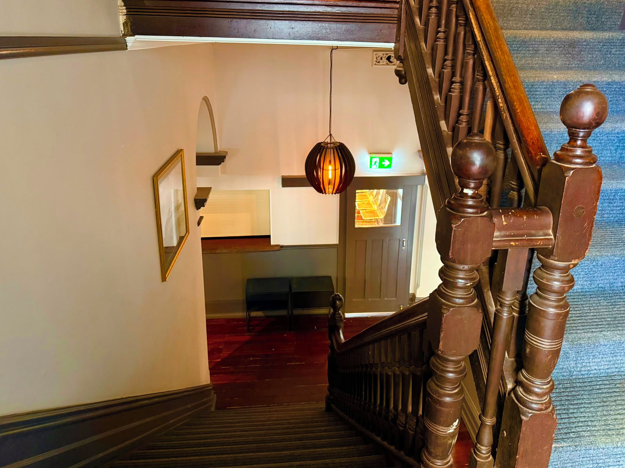 A staircase with a wooden handrail and a hanging light fixture.