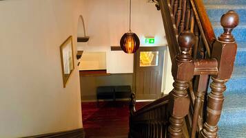 A staircase with a wooden handrail and a hanging light fixture.