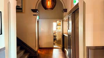Un couloir doté d’un plancher en bois, d’un plafond en arc de cercle et d’un luminaire suspendu.