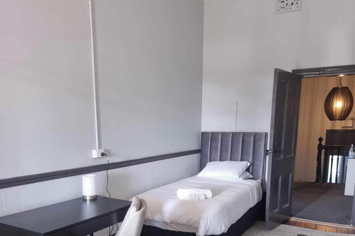 A bedroom with a bed, a desk, a chair, and a TV.