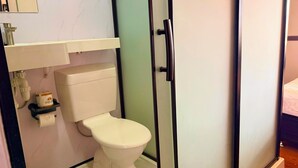Une salle de bain avec des toilettes, un lavabo blanc et un miroir au-dessus.