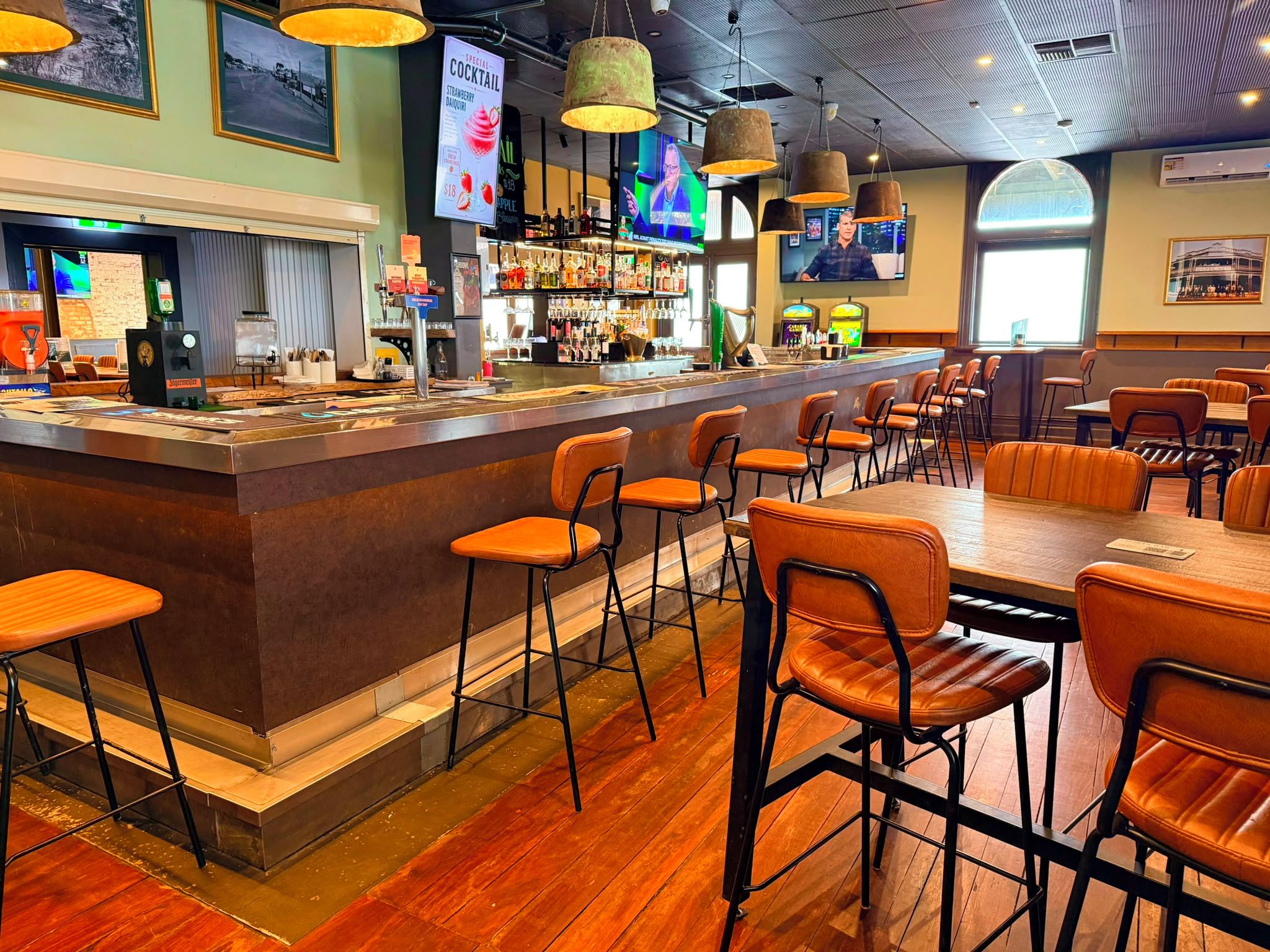 A bar area with stools, a counter, and a television screen.