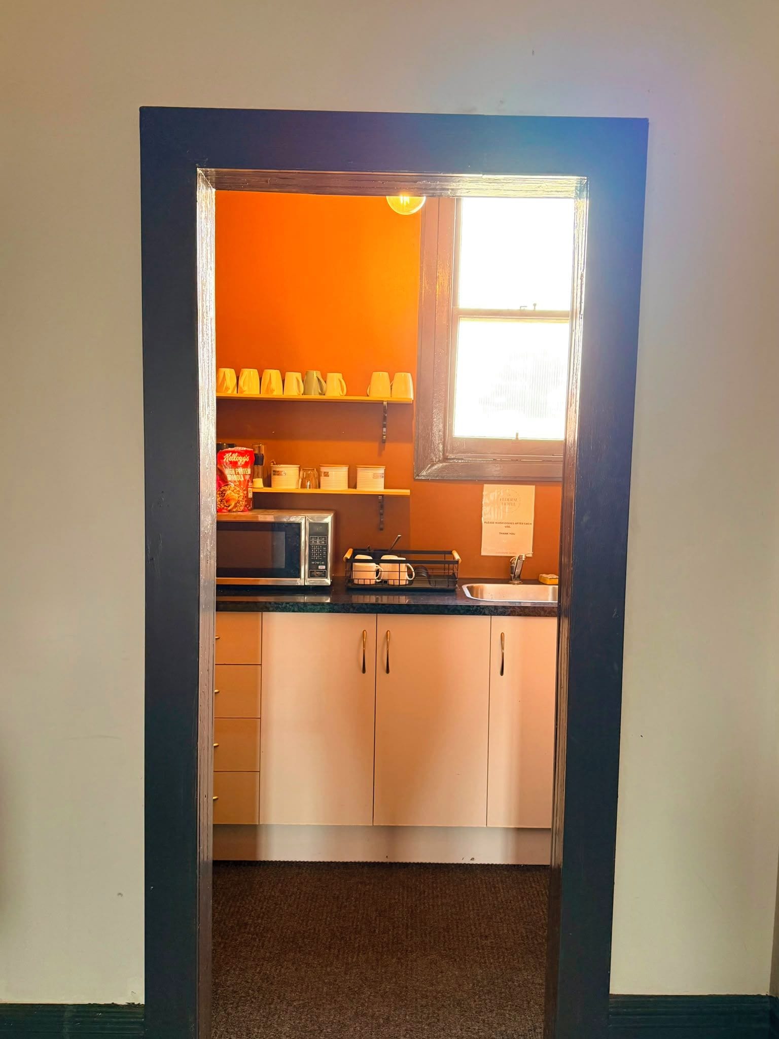 Una cocina con microondas, hervidor y tetera en la encimera.