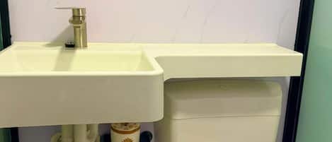 A bathroom with a white sink, mirror, and toilet.