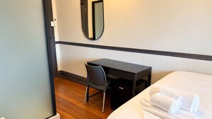 Une chambre d’hôtel avec un lit, un bureau, une chaise et un miroir.