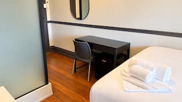 A hotel room with a bed, a desk, a chair, and a mirror.