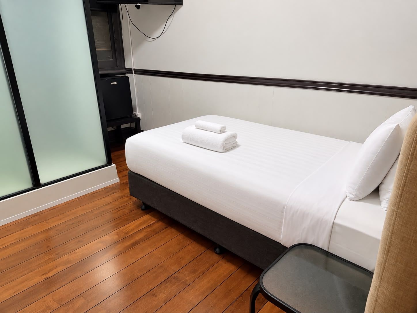 A hotel room with a single bed, a small table, and a television.