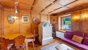Un intérieur en bois comprenant une table à manger, des chaises, un canapé, un meuble et une fenêtre donnant sur un paysage agréable.