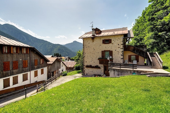 A traditional building with a stone facade, wooden shutters, and a metal roof.