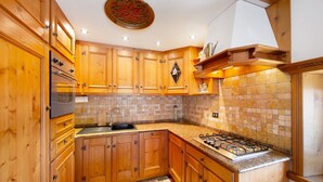Une cuisine avec des meubles en bois, une cuisinière à gaz et un dosseret carrelé.