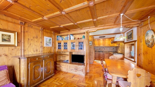 Un intérieur en bois comprenant une table à manger, des chaises, un buffet et un téléviseur.