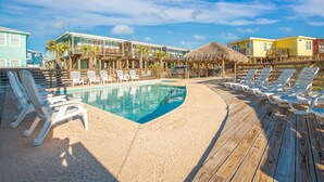 A pool area with lounge chairs and a wooden deck. - Golf Cart Included at Sandy Coral! Pet Friendly! (Port Aransas)