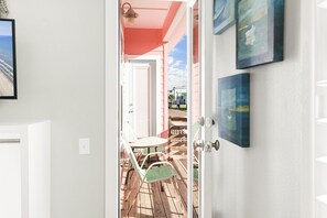On aperçoit, à travers une porte, une pièce dotée d’une terrasse en bois, d’une table et de chaises.