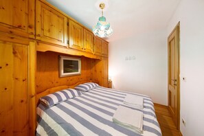 Une chambre aux murs lambrés, avec un lit, un luminaire suspendu et une porte.
