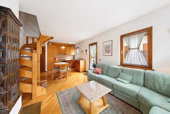 A living room with a sofa, a table, a staircase, and a kitchen area.