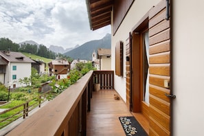 A wooden balcony with a view of a village and mountains.
