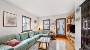 Una sala de estar con un sofá verde, una mesa de centro, un televisor y un aparador con platos decorativos.