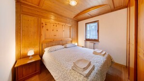 A wooden-paneled bedroom with a bed, nightstand, and window. - Apartment 'Michaela A Vinigo' with Mountain View, Private Terrace and Wi-Fi (Vinigo)