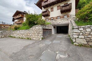 Une entrée en pierre menant à un bâtiment doté de balcons en bois et d’un porche.