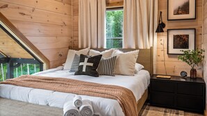 A wooden-paneled bedroom with a bed, curtains, framed pictures, and a nightstand. - Central Loc*Luxury*Indoor Pool *Hot Tub *Dollywood (Pigeon Forge)