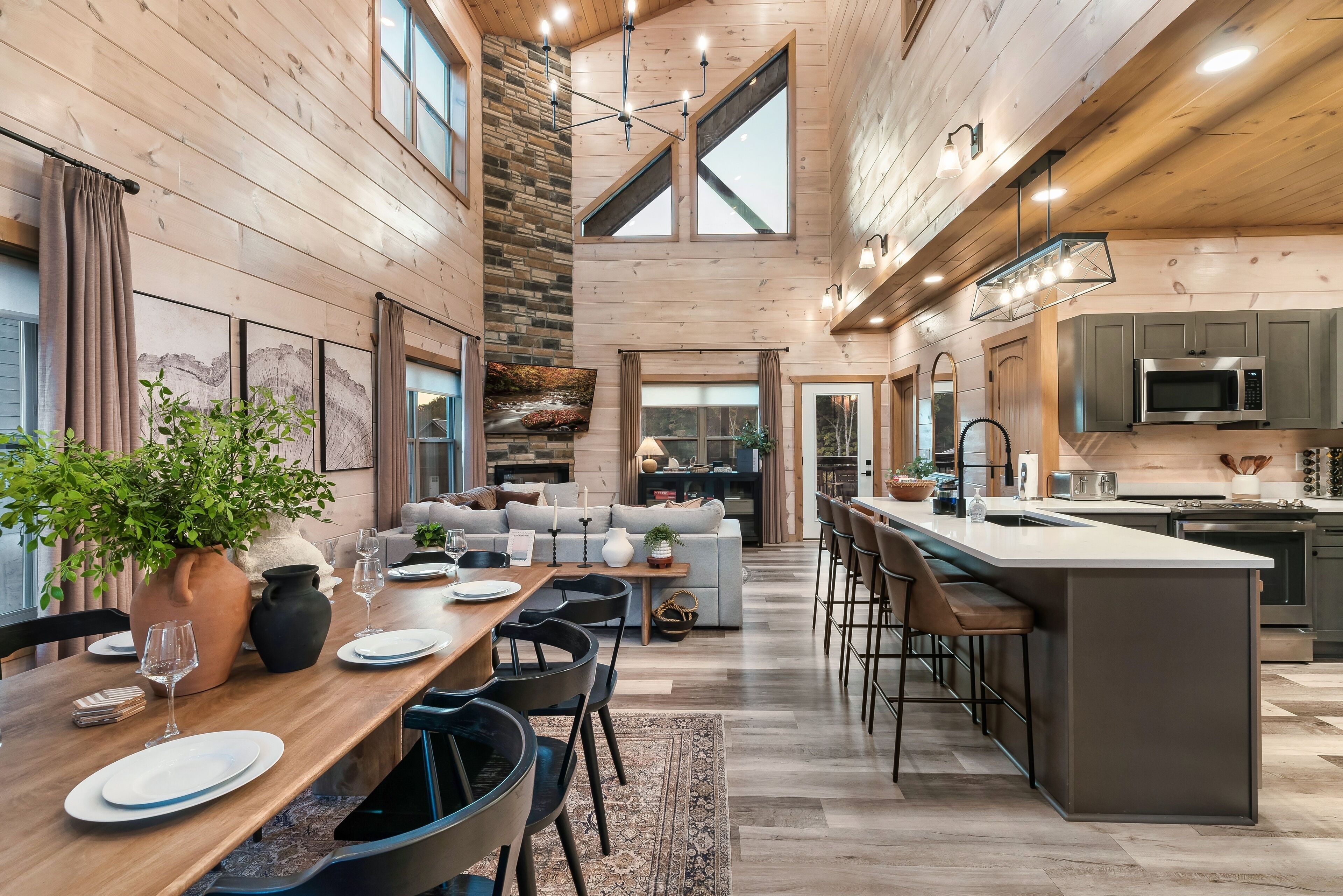 A spacious kitchen with a central island, a dining area with a wooden table and chairs, and a living area with a sofa and a fireplace.